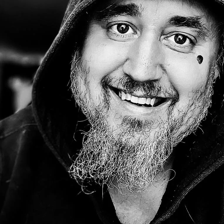 Casey Keith Black and white portrait of Casey Keith, bearded, and smiling wearing a hoodie.